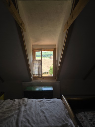 Odaia 1828 — fereastră cu vedere spre deal, sub acoperișul în pantă