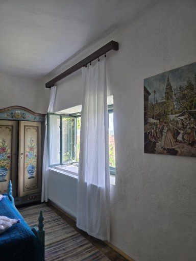 Odaia Pridvorului — fereastră cu perdele albe și dulap pictat cu motive florale